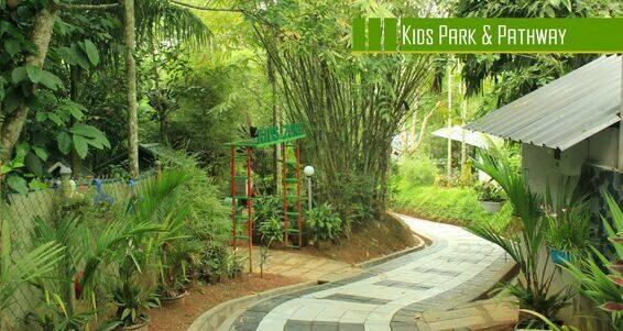 "Kids' park with a scenic pathway at Vintage Garden Resort in Wayanad, surrounded by lush greenery and play areas."