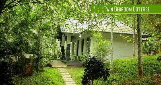 "Exterior view of a Twin Bedroom Cottage at Vintage Garden Resort, surrounded by lush greenery, featuring a quaint veranda and traditional architecture in a peaceful garden setting."

